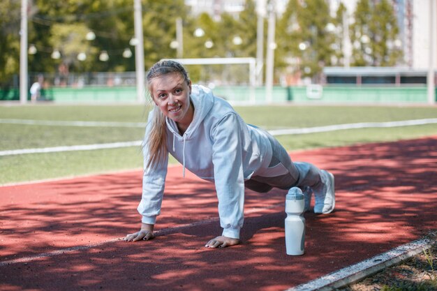 Squatting.young beauty girl do exercises at the stadium