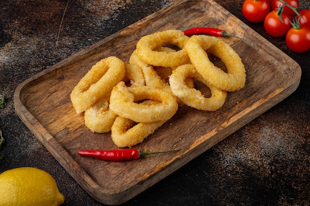 Squid rings or onion in breadcrumbs ingredients set, on serving board, on old dark rustic table background