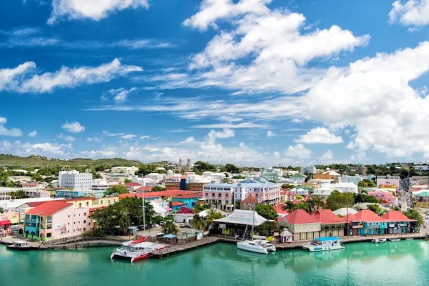 St John Antigua March 05 2016 traveling and vacation cute houses at harbor with yacht boat ship transportation in bay with sea ocean water blue cloudy sky sunny summer on natural background