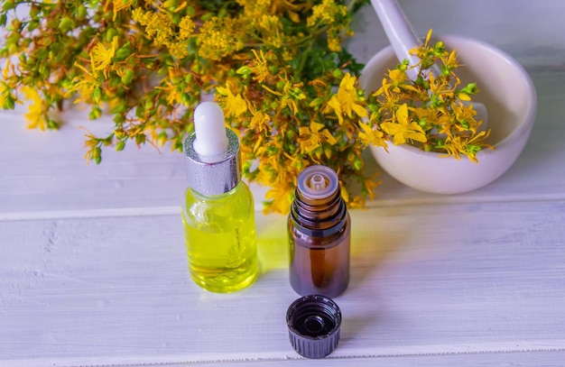 St John's wort flower oil in a glass bottle on a wooden background