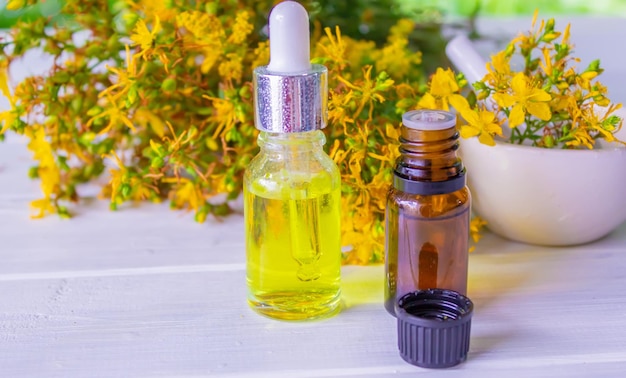 St John's wort flower oil in a glass bottle on a wooden background