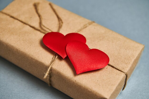 St. Valentines Day concept. A Saint Valentine Day's gift in eco paper and red hearts on a gray background