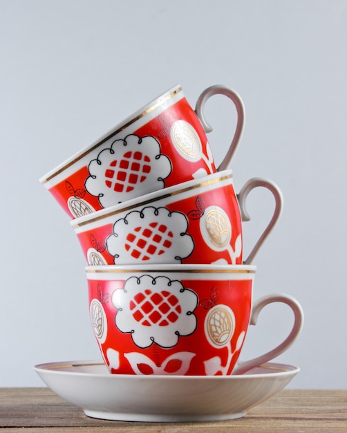 Stack of antique ceramic cups on a wooden table against a white wall