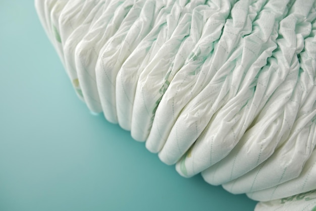 Stack of baby diaper on light green background