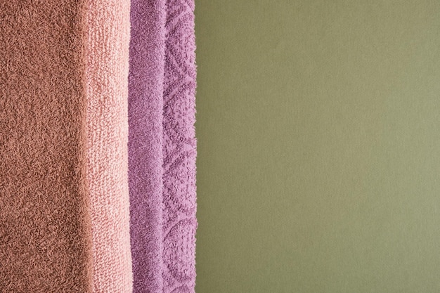 Stack of bath towels on green wooden background closeup copy space