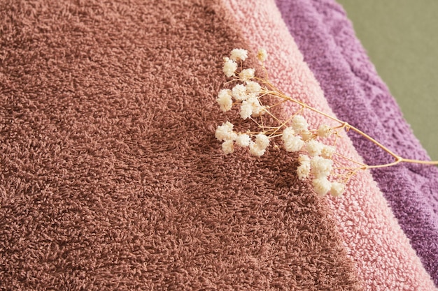 Stack of bath towels on green wooden background closeup copy space