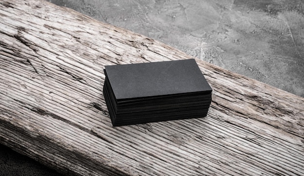 Stack of black blank name cards on wooden background mockup for branding company style