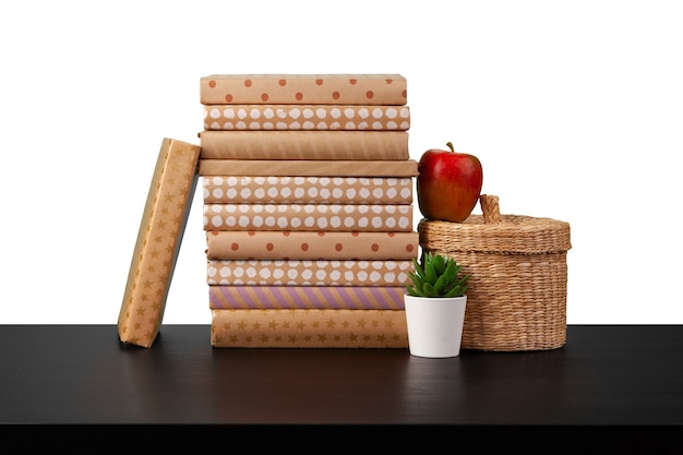 Stack of books and apple on tabletop against white background