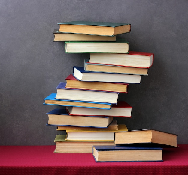 Stack of books in the colored covers on the table with a red tablecloth. Still life with books.