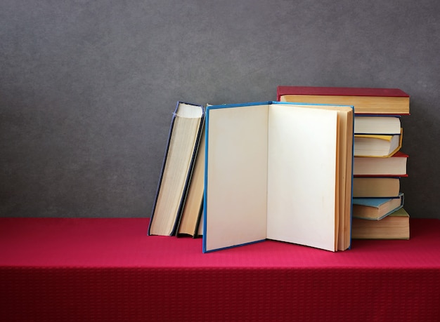 A stack of books in the colored covers on the table with a red tablecloth.