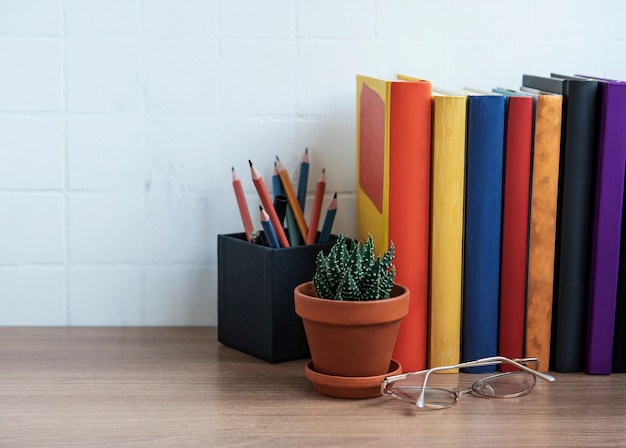 Stack of books on the desktop. Various books and office supplies on the table