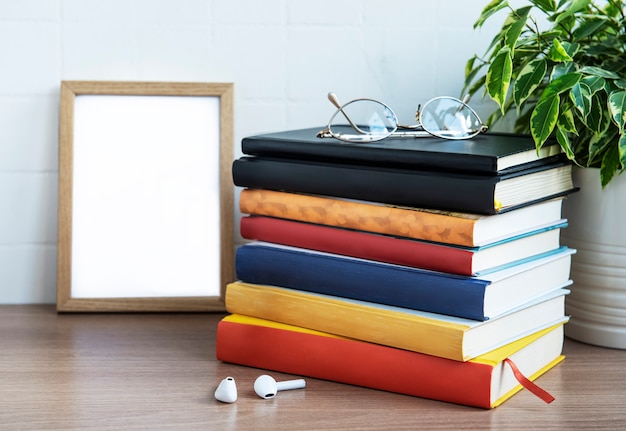 Stack of books on the desktop. Various books and office supplies on the table