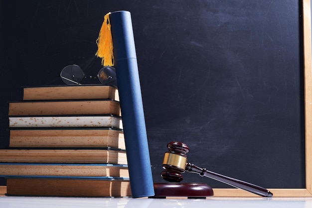 Stack of books eyeglasses scroll of certificate and gavel hammer