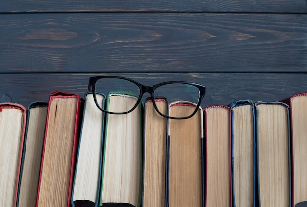 A stack of books and reading glasses on a gray wooden background the concept of reading books on paper