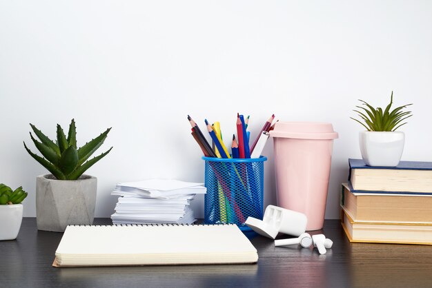 Stack of books, spiral notebooks, ceramic cup with coffee and colorful pencils 