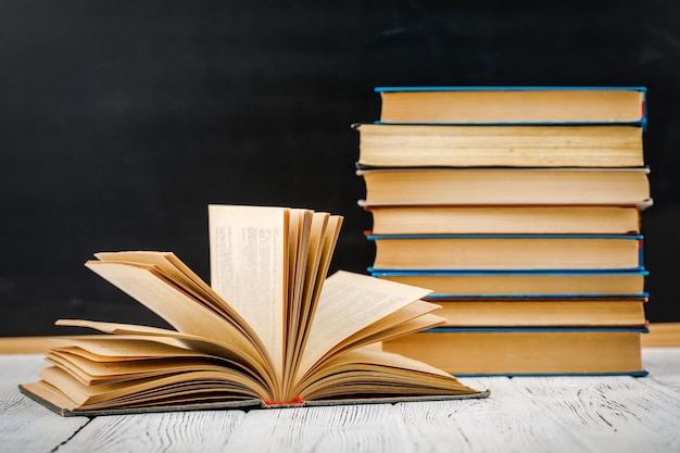 A stack of books on a white table against a blackboard.