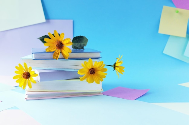 A stack of books with bookmarks from fresh chamomile flowers, on the background of note paper