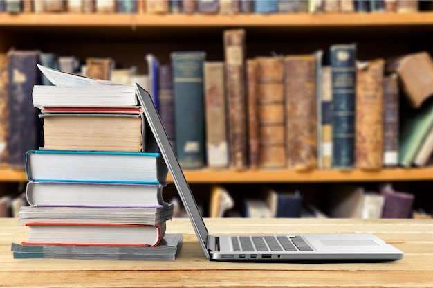 Stack of books with laptop on table