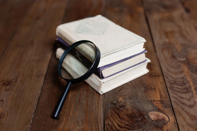 Stack of books with magnifying glass on wooden table world book day