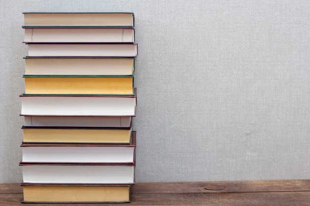 A stack of books on a wooden shelf and a gray