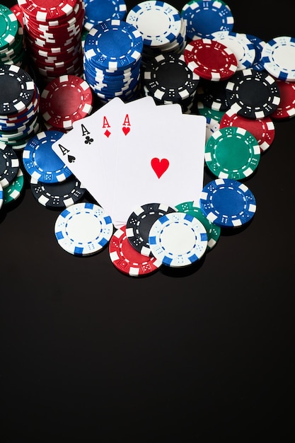 Stack of casino gambling chips and cards isolated on black reflective background