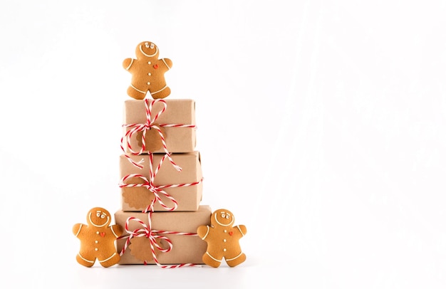 Stack of Christmas gifts boxes in craft paper
with crunchy gingerbread men cookies. Merry Christmas concept on white background