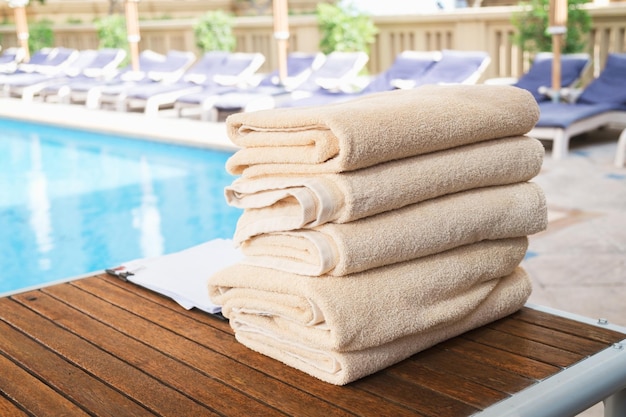 Stack of clean towel on wooden table near pool for service customer