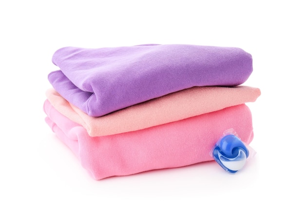 Stack of clothes and laundry pod on white background