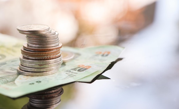 Stack of coins and banknote in bokeh background