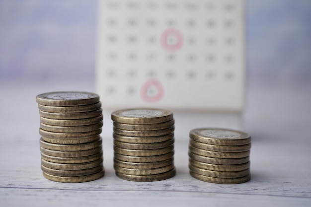 Stack of coins and calendar on table