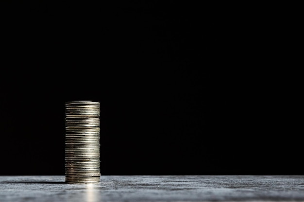 Stack of coins on grey table and black background Startup capital concept with copy space