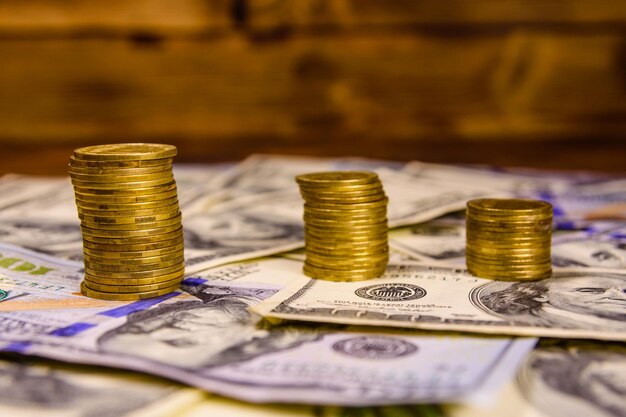 Stack of the coins on the one hundred dollar bills