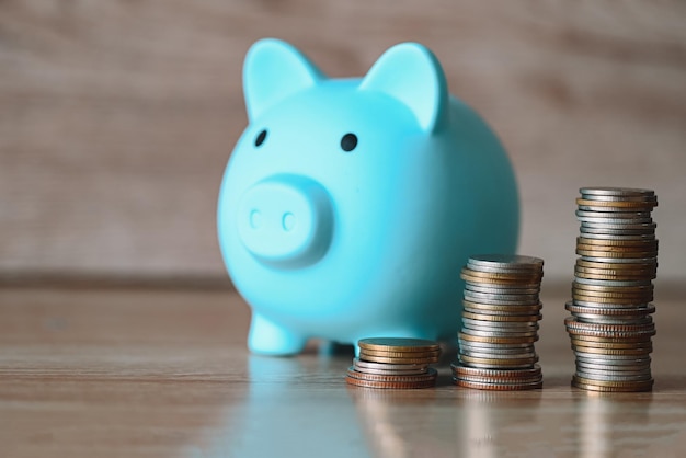 Stack coins and piggy bank on wooden background blue piggy bank saving money for education study or investment concept