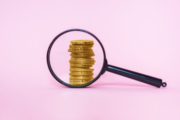 Stack of coins through a magnifier on a pink background. Euro coins.