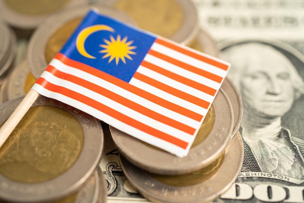 Stack of coins with Malaysia flag and US dollar banknotes