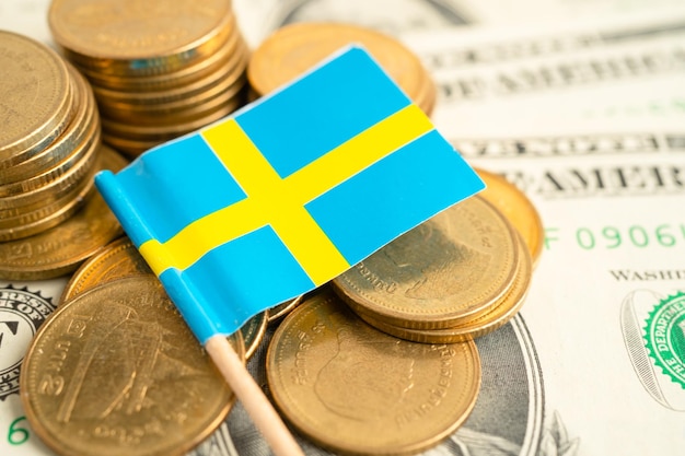 Stack of coins with Sweden flag and US dollar banknotes