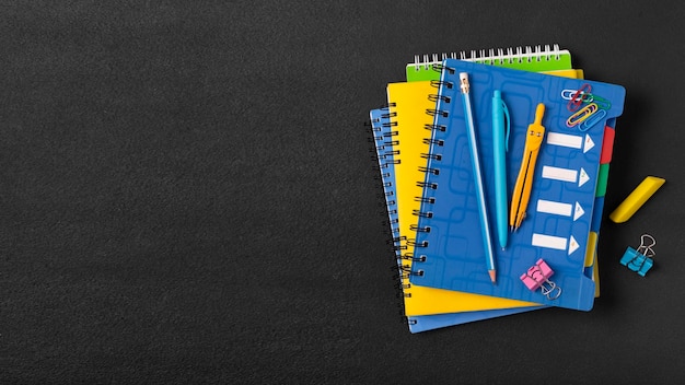 Photo stack of colored school notebooks and an alarm clock