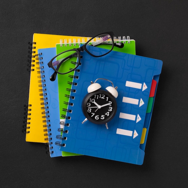 Stack of colored school notebooks and an alarm clock