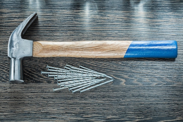 Stack of construction nails claw hammer on wooden board