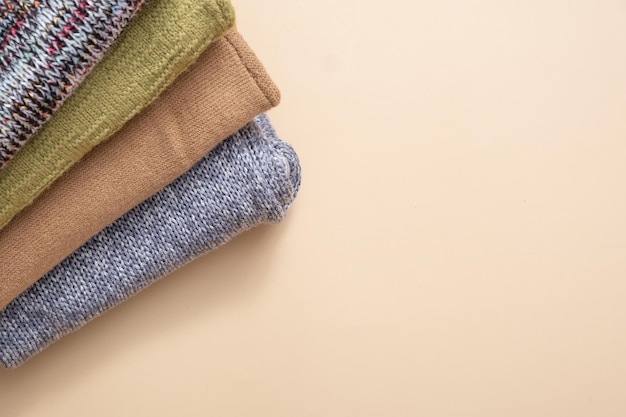 A stack of cozy knitted sweaters on beige background Warm concept