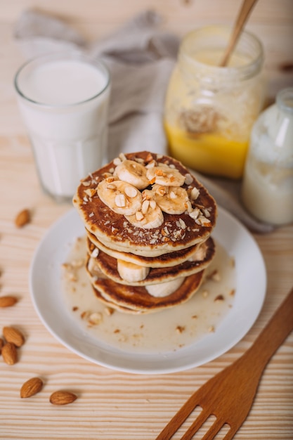 Stack of delicious pancakes with honey, nuts and slices of banana.