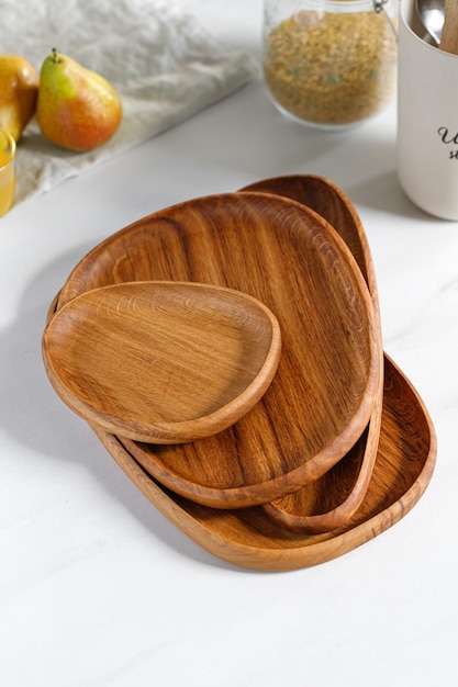 Stack of different Wooden oak dishes boards trays Empty wooden plates on kitchen white table