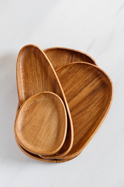 Stack of different Wooden oak dishes boards trays Empty wooden plates on kitchen white table