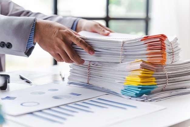 Stack of documents pile of papers on office desk employee's table closeup Asian people