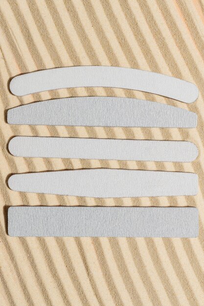 Photo stack of flexible emery boards of different shapes for manicures and pedicures on sandy background