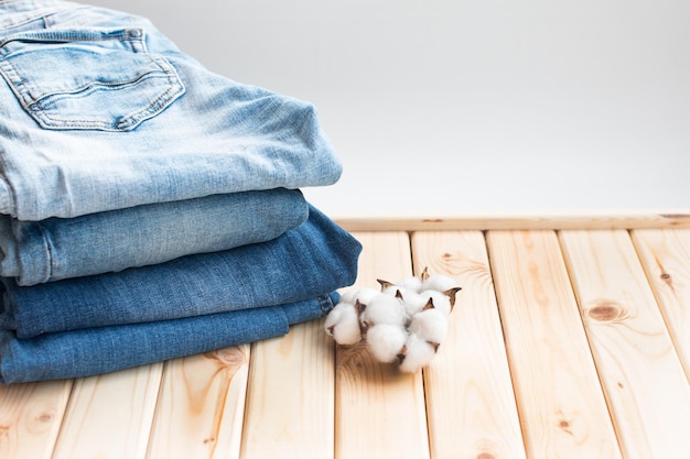 A stack of folded jeans in various shades of cotton with knitted hats and a sweater