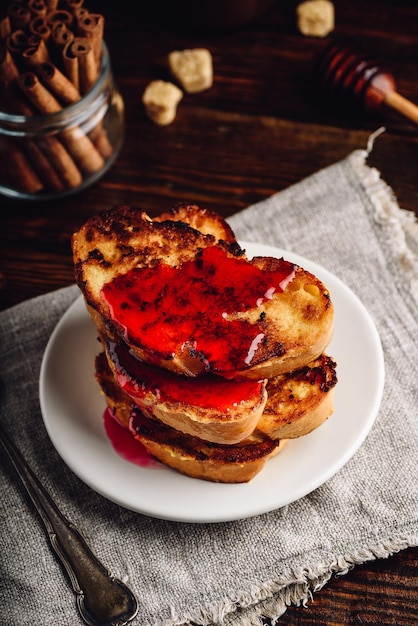 Stack of french toasts with berry syrup on white plate