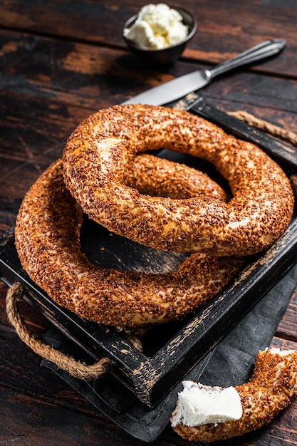 Stack of fresh baked Turkish simit bagel with kaymak. Wooden background. Top view.