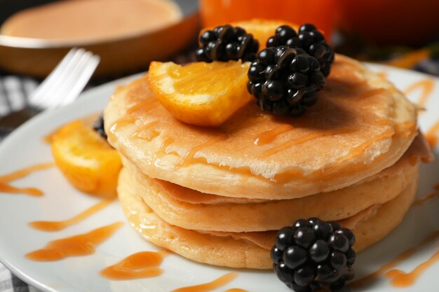 Stack of fresh pancakes with fruits on plate closeup