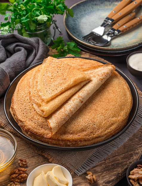 A stack of fried pancakes on a dark background. Maslenitsa, traditional Russian blini. Top view, vertical.